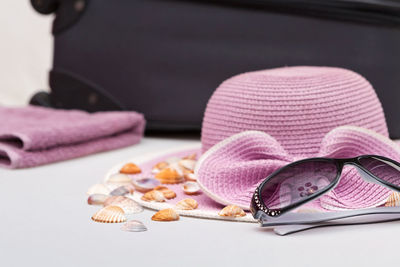 Close-up of sunglasses with seashells and hat on table