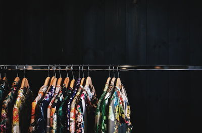 Clothes hanging from coathangers on rack against wall in shop