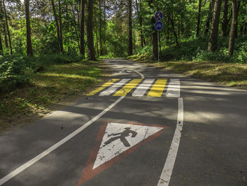 Road sign by trees in forest