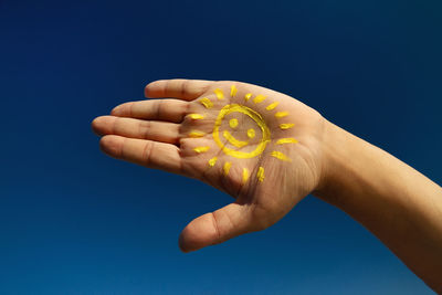 Cropped image of painted hand against blue sky