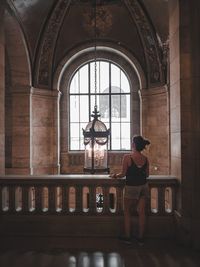 Rear view of woman standing by railing in building