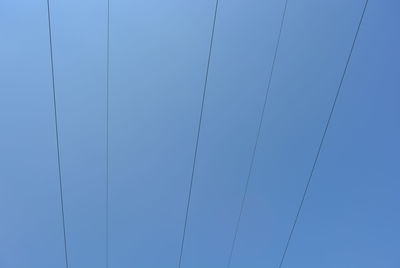 Low angle view of power lines against clear blue sky