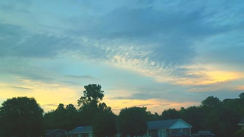 Silhouette trees against cloudy sky at sunset