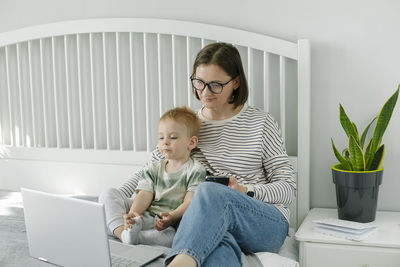 Young woman using laptop while sitting on sofa at home