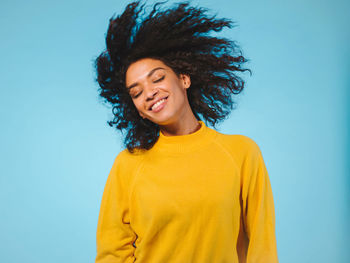 Young woman with tousled hair against blue background