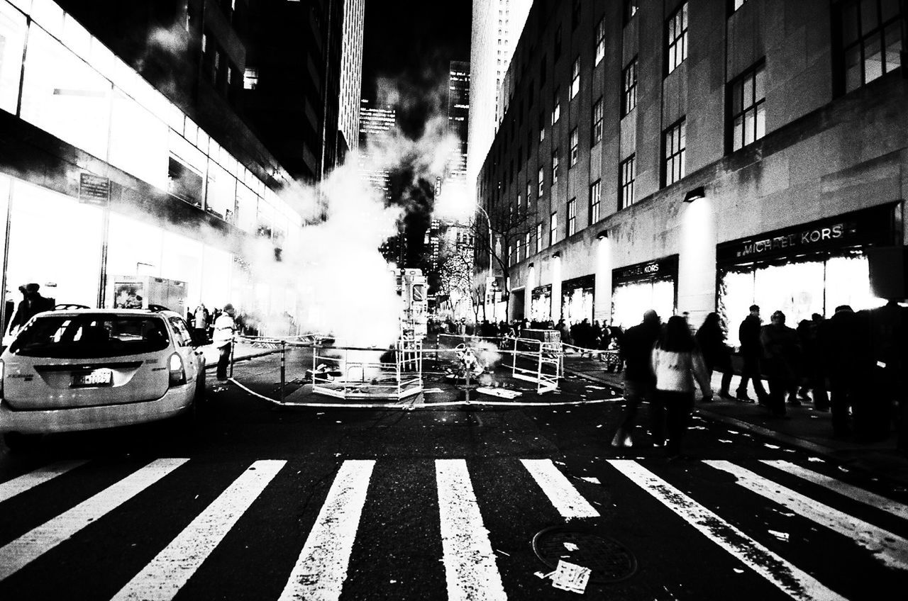 transportation, city, street, building exterior, car, architecture, city life, built structure, city street, mode of transport, land vehicle, road, road marking, person, incidental people, zebra crossing, men, text, large group of people