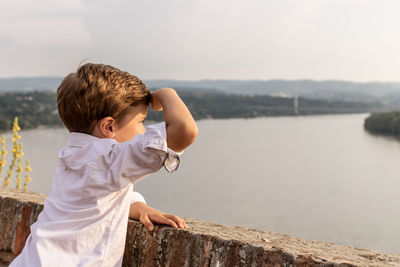 Small boy enjoying the view of the river at sunset. copy space.