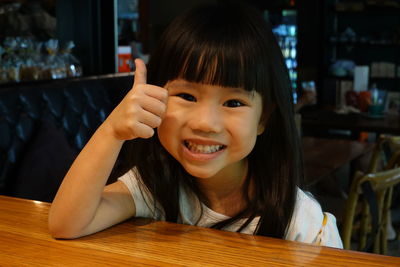 Portrait of smiling girl on table at restaurant