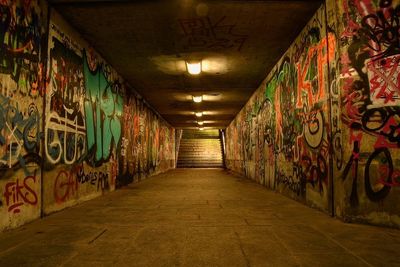 Graffiti on wall in illuminated tunnel