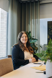 Portrait of smiling businesswoman sitting at desk in office