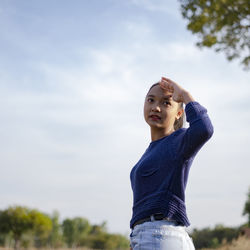 Young woman looking at camera against sky