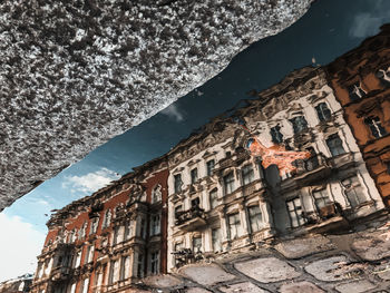 Reflection of building in water puddle on footpath