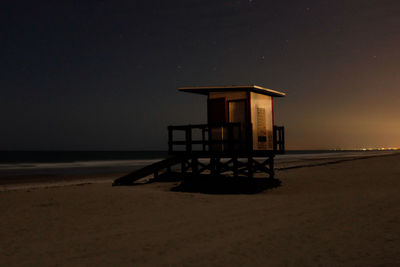 Lifeguard hut on beach against sky at night