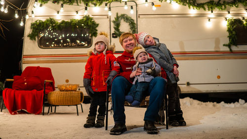 Portrait of smiling father with kids sitting against van