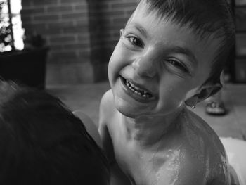 Close-up portrait of smiling boy taking bath at home