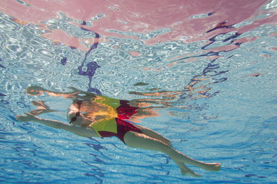 Low angle portrait of young female model swimming in pool
