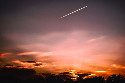 Low angle view of vapor trail in sky during sunset