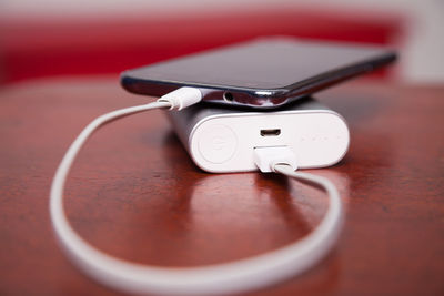 Close-up of mobile phone connected to portable charger on table