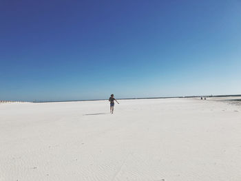 Man on beach against clear blue sky