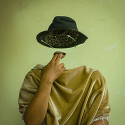 Midsection of person holding umbrella standing against wall