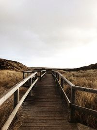 Empty wooden footbridge along landscape