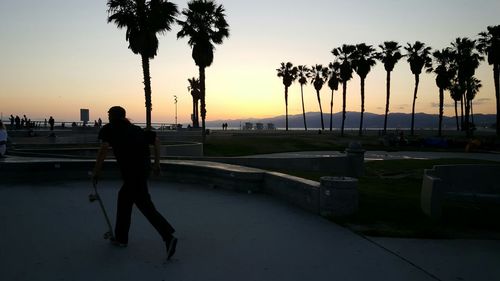 Full length of man running with skateboard at park during sunset