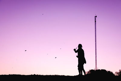 Silhouette man standing against sky during sunset