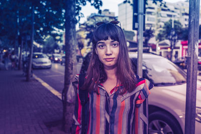 Portrait of young woman standing on street in city