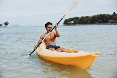 Man kayaking in sea against sky