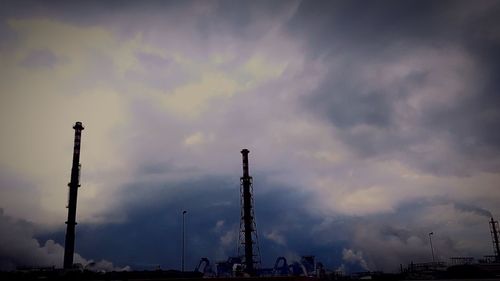 Low angle view of silhouette smoke stack against sky during sunset