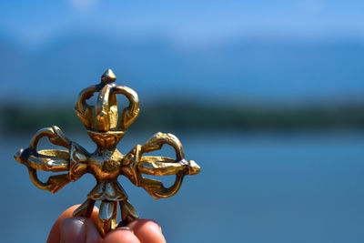 Cropped hand of person holding decoration against sky