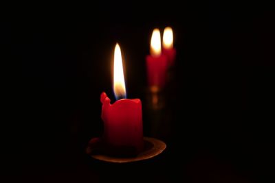 Close-up of lit candle in darkroom