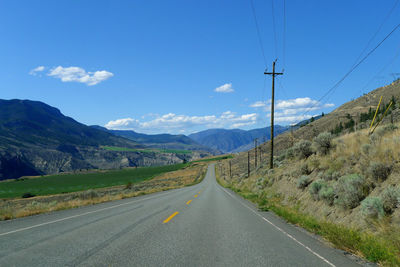 Road by mountains against sky