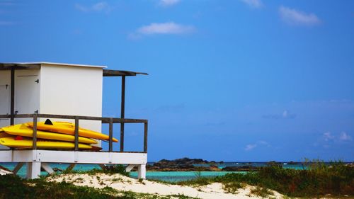 Lifeguard hut on beach against blue sky