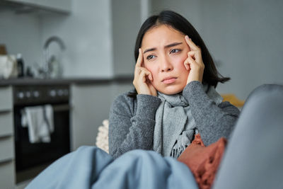 Portrait of young woman sitting on sofa at home