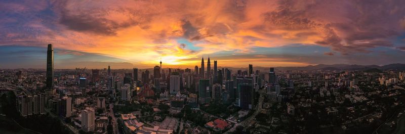 Panoramic view of city against cloudy sky during sunset
