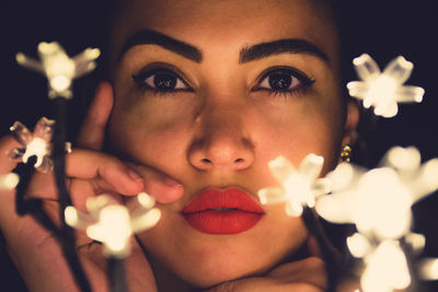 Close-up portrait of young woman with illuminated lights