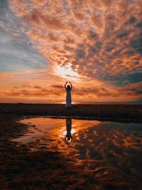 Full length of man standing on beach against sky during sunset