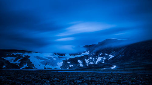 Scenic view of snowcapped mountains against blue sky