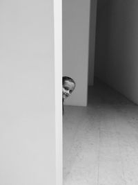 Portrait of girl hiding behind wall at home