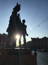 Statue on street in city against sky