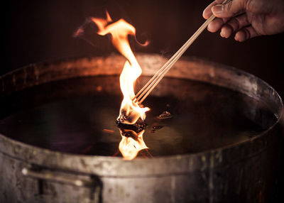 Cropped hand of woman holding lit diya with sticks