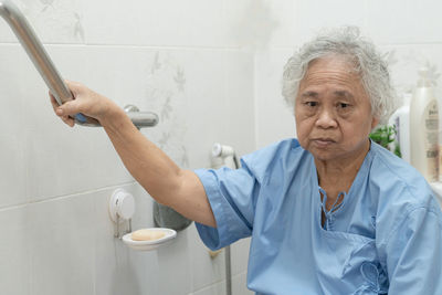 Portrait of woman with arms raised against wall