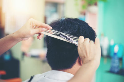 Rear view of woman cutting man hair in salon