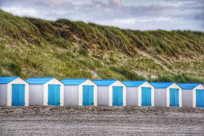 Beach huts on field against blue sky