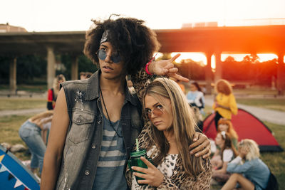 Portrait of smiling men and women with friends in background at music festival