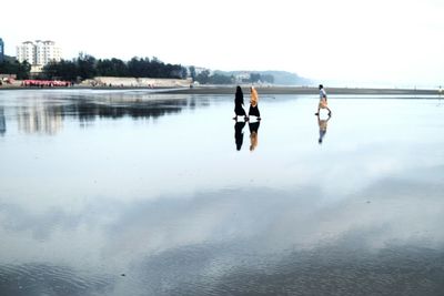 People on lake against sky