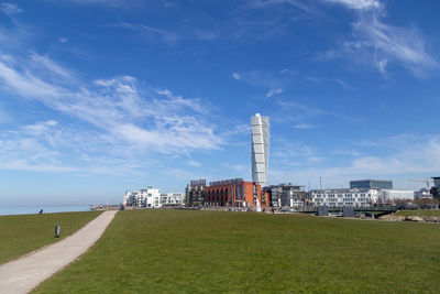 Road by buildings against sky