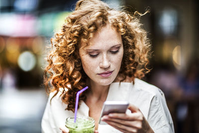 Portrait of woman holding mobile phone outdoors