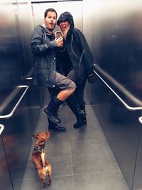 Portrait of young man and woman with dog on floor in elevator